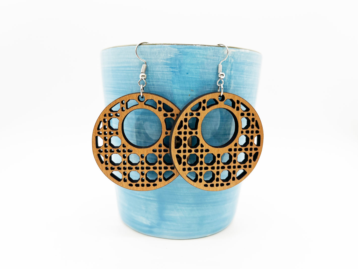 a pair of wooden earrings sitting on top of a cup