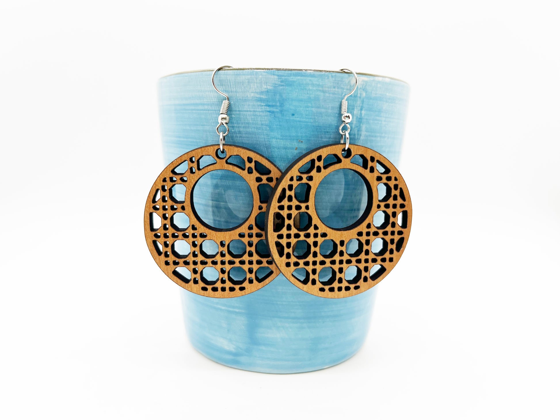 a pair of wooden earrings sitting on top of a cup