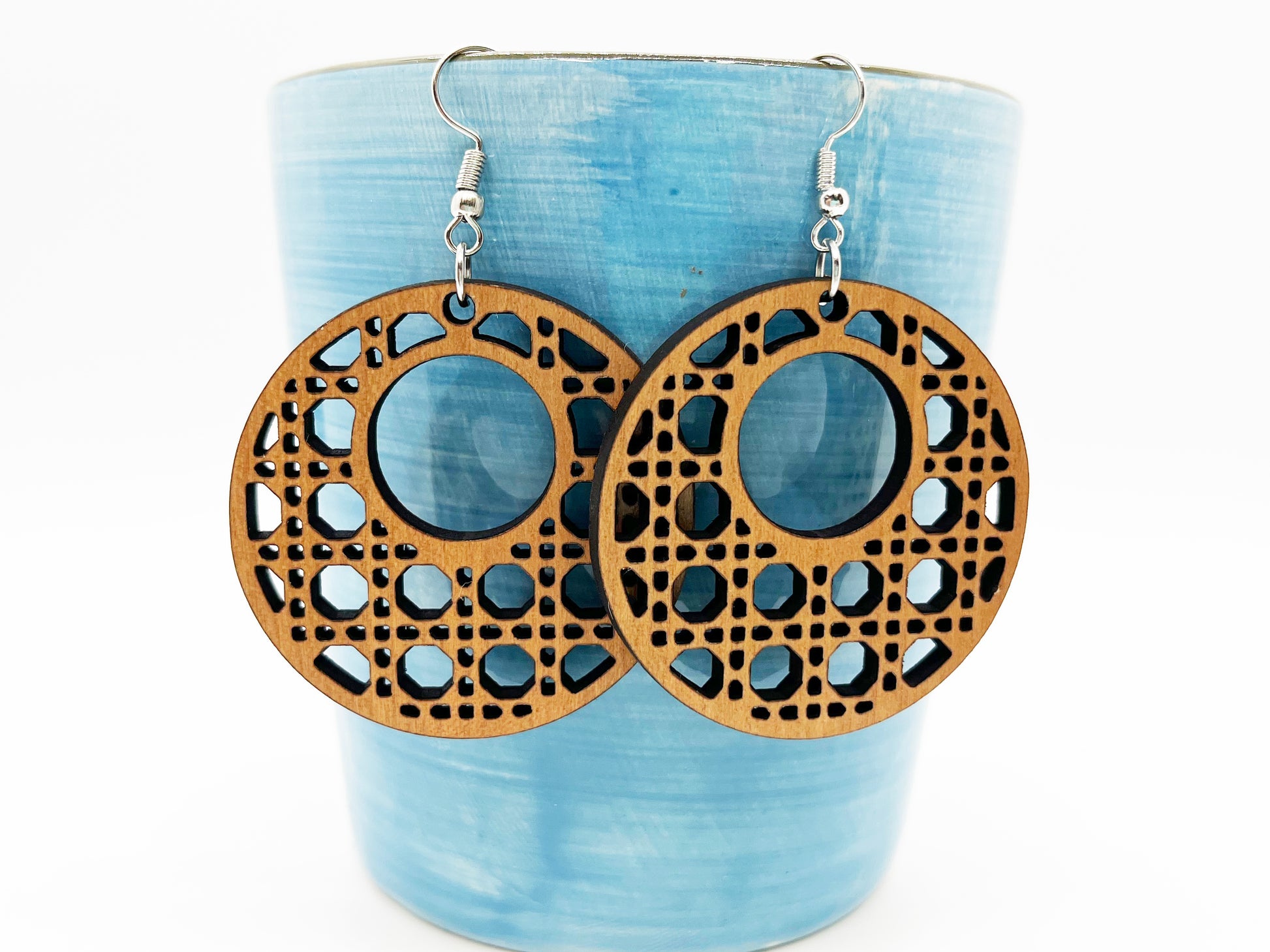 a pair of wooden earrings sitting on top of a cup
