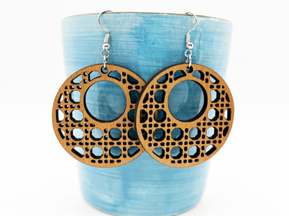 a pair of wooden earrings sitting on top of a cup