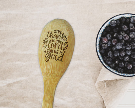 a bowl of blueberries next to a wooden spoon