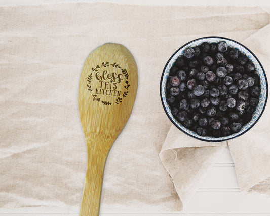 a bowl of blueberries next to a wooden spoon