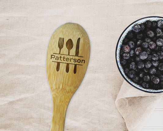 a bowl of blueberries next to a wooden spoon