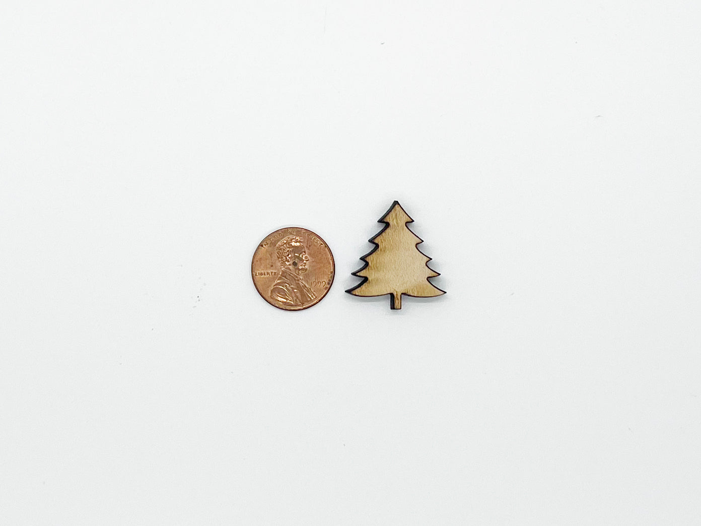 a small wooden christmas tree next to a penny