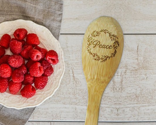 a bowl of raspberries next to a wooden spoon