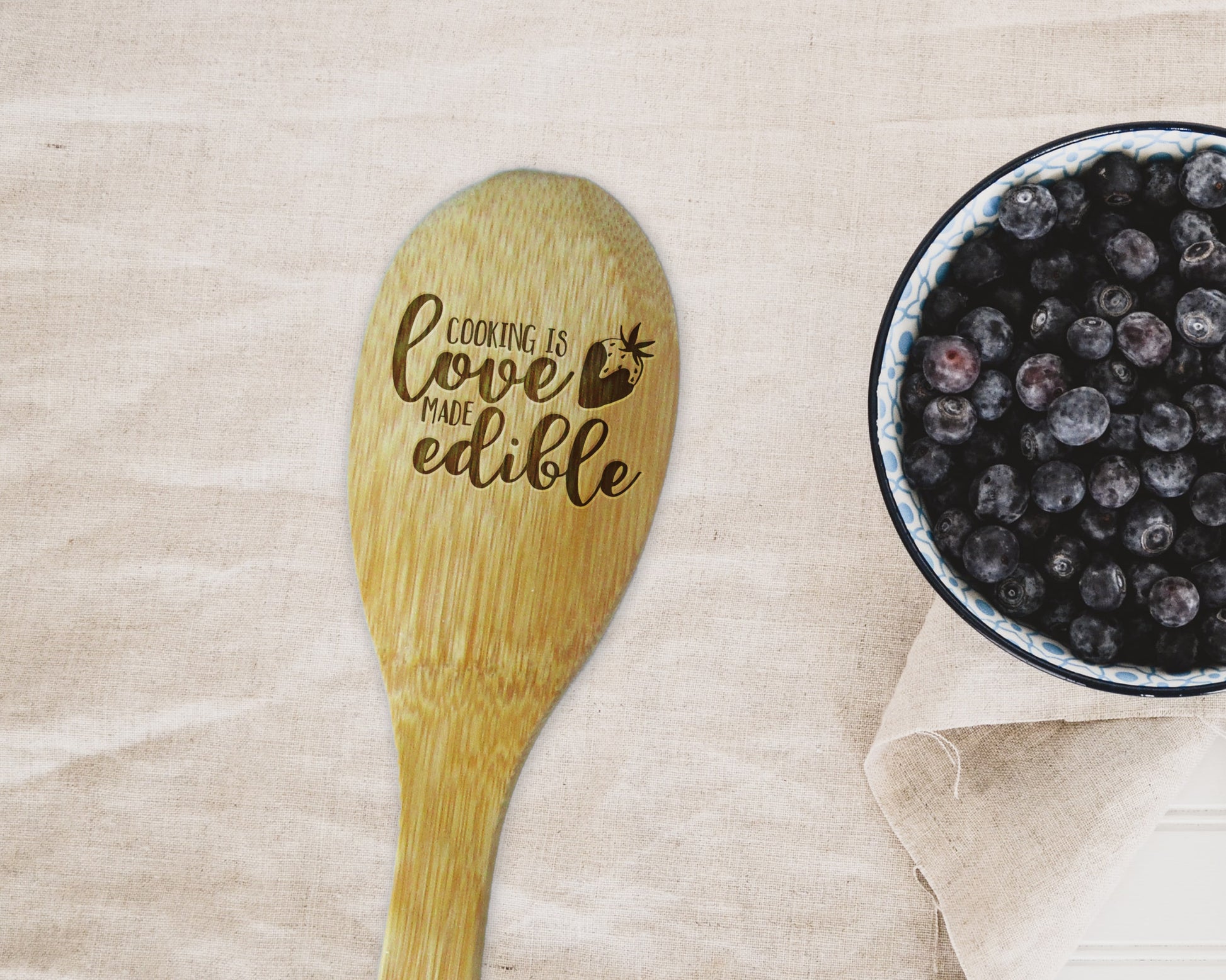 a bowl of blueberries next to a wooden spoon