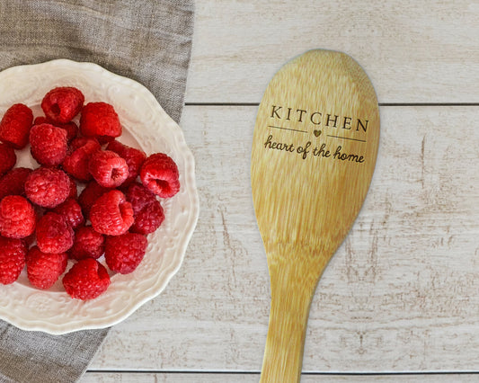 a bowl of raspberries next to a wooden spoon