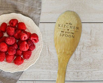 a bowl of raspberries next to a wooden spoon